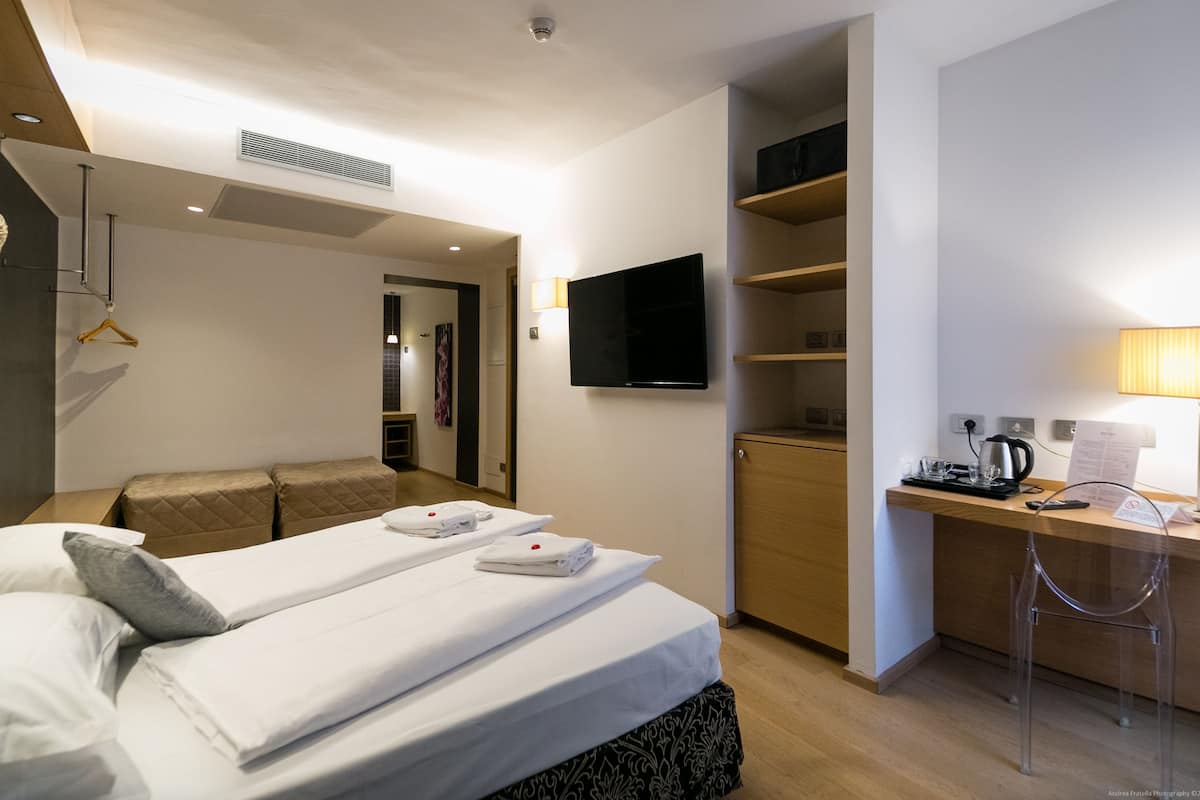 A hotel room with a bed, a desk, a TV, and a bathroom.
