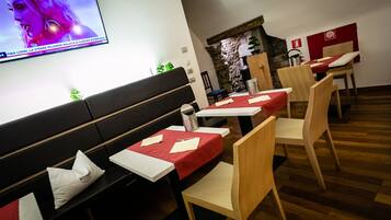 Un restaurante con mobiliario de madera, manteles rojos y una pared de piedra.