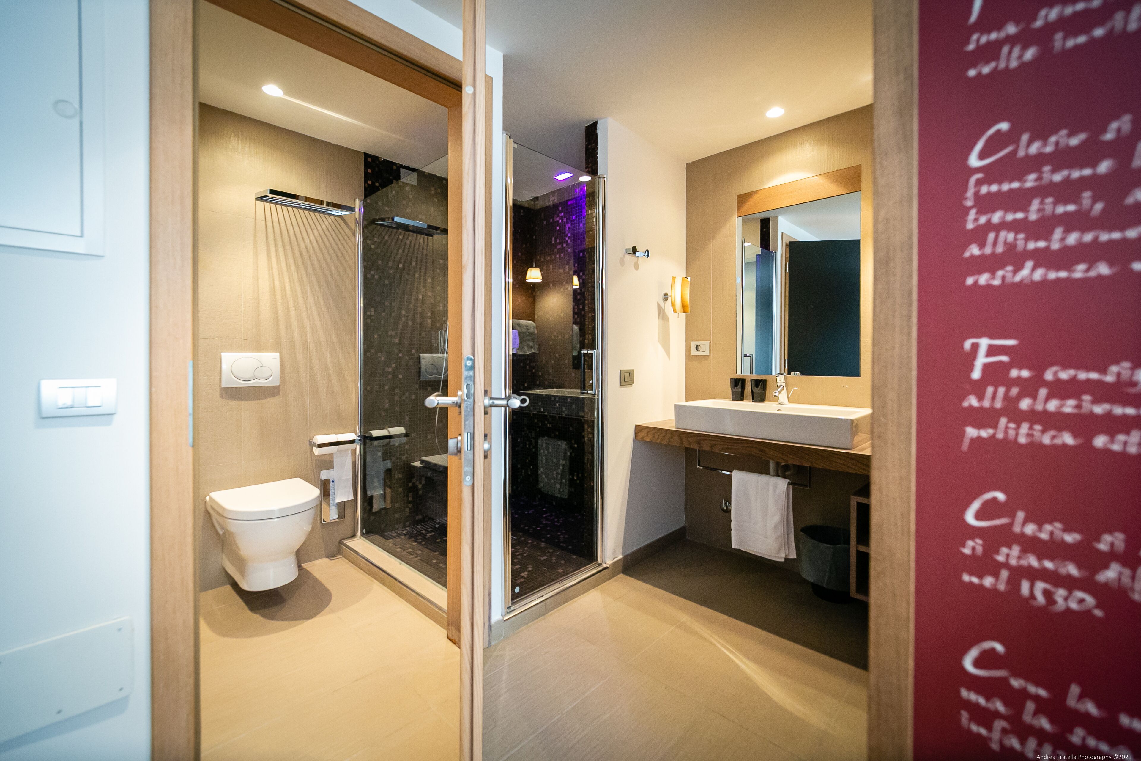 Un bagno moderno con box doccia in vetro, un water bianco e un mobile lavabo con specchio.