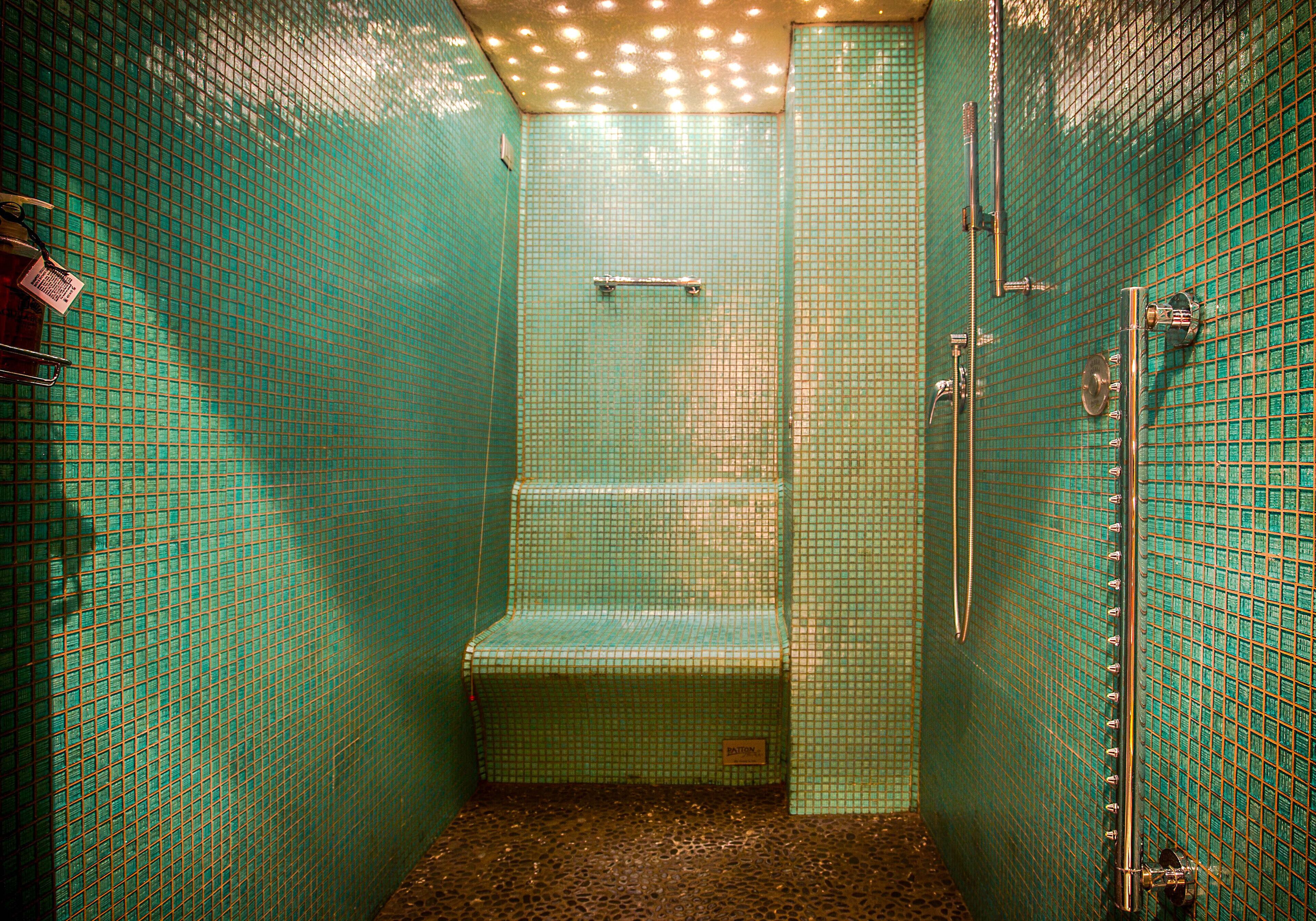 Ein kleines Badezimmer mit Fliesen, einer Sitzbank, einer Dusche und einem WC.