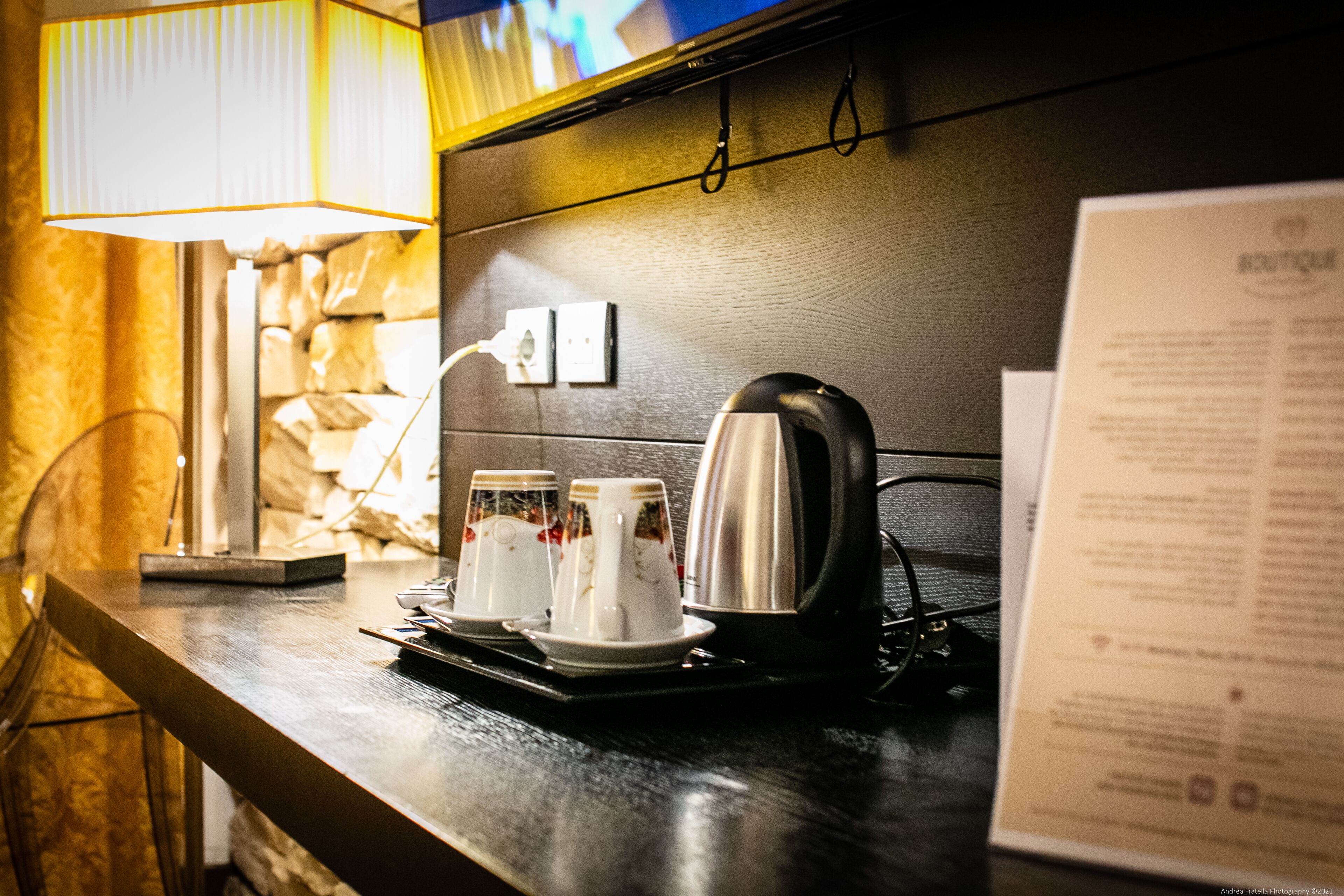 Un coin bar d’hôtel avec une machine à café, deux tasses et un menu posé sur le comptoir.