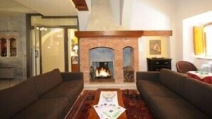 A living room with a fireplace, two sofas, and a coffee table. - Albergo Duomo (Montepulciano)
