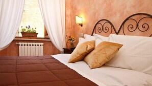A neatly made bed with a brown quilt, white pillows, and a headboard with a decorative design. - Albergo Duomo (Montepulciano)