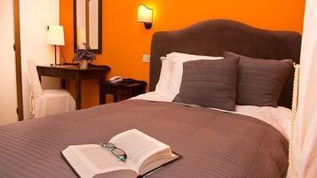 Une chambre d’hôtel avec un grand lit, une table de chevet avec une lampe, un miroir et une petite table de nuit avec un téléphone.