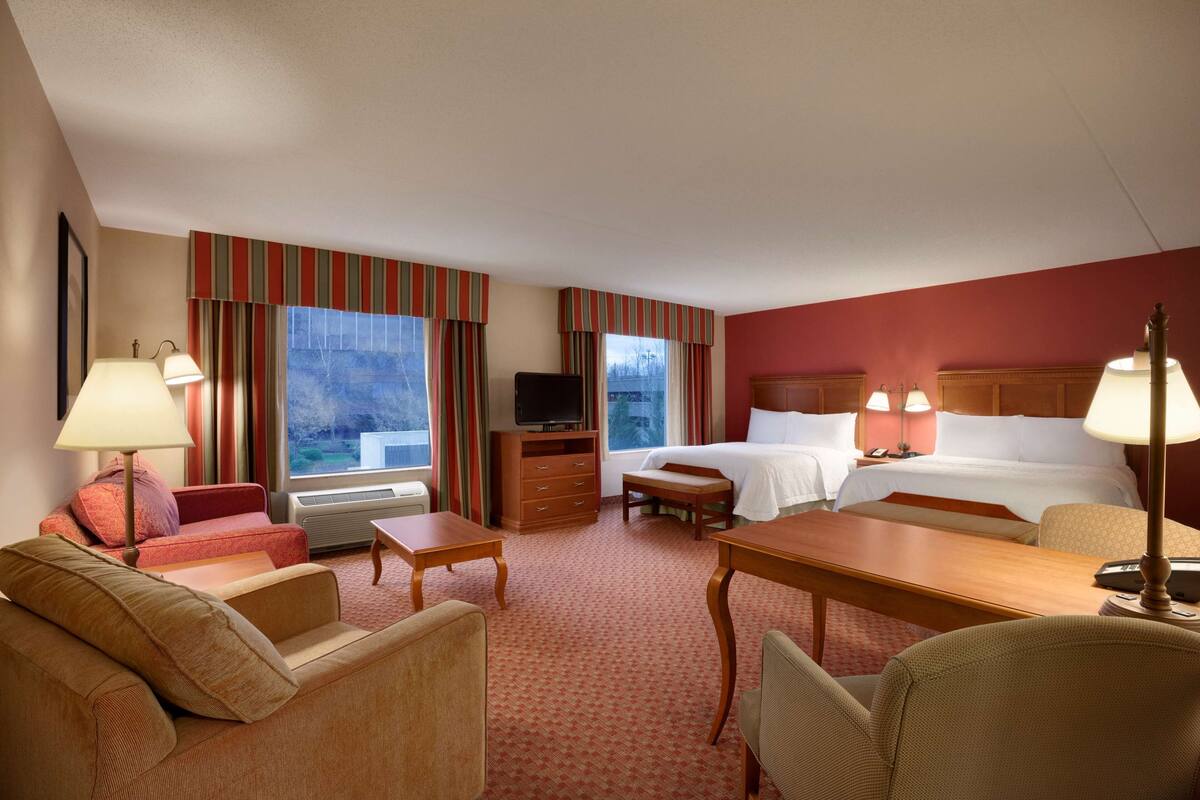 Une chambre d’hôtel avec deux lits, une télévision, un bureau et un canapé.