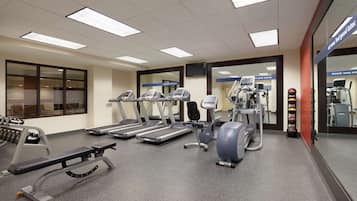 Un gimnasio con cintas de correr, elípticas y equipo de pesas.