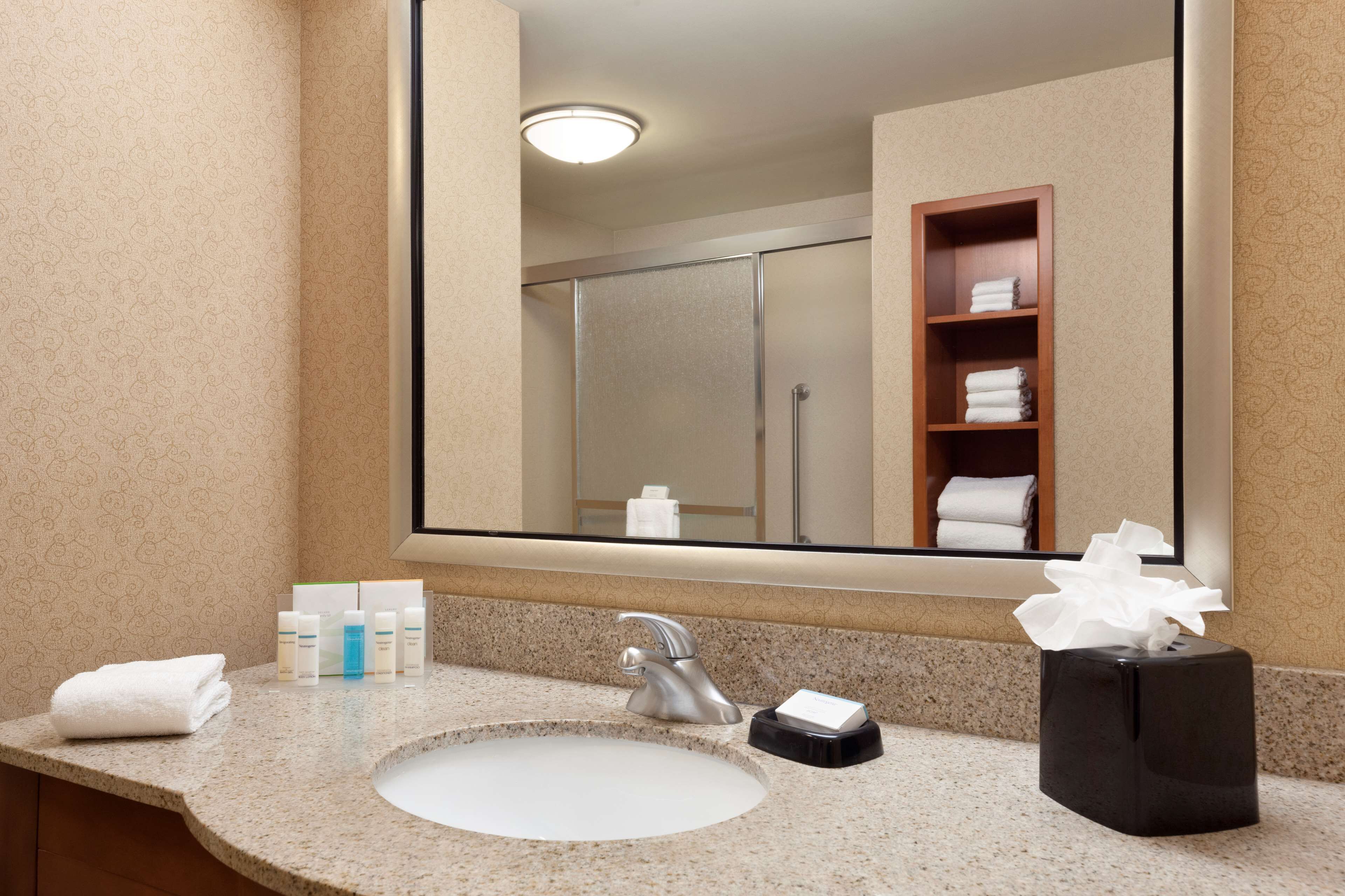 A bathroom with a sink, mirror, and toiletries.