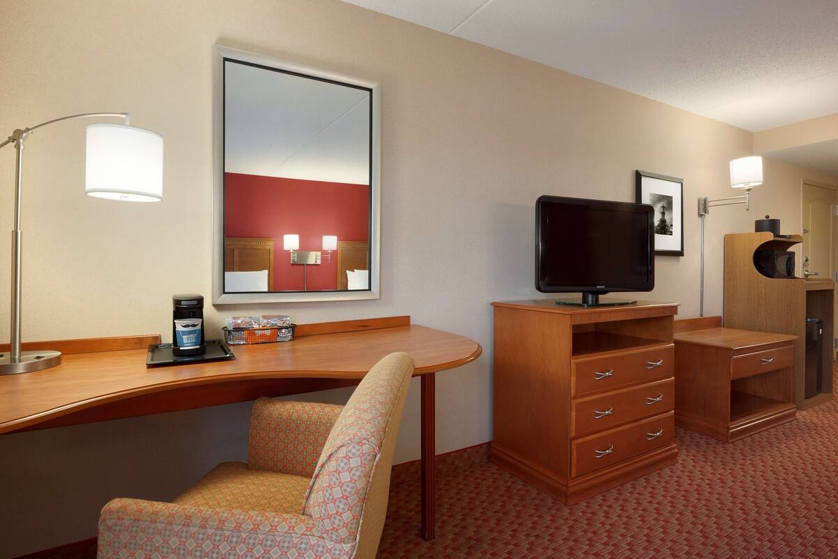 Une chambre d’hôtel équipée d’un bureau, d’une chaise, d’une télévision et d’une armoire.