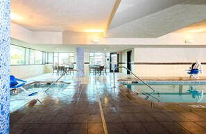 A hotel lobby with a pool area, including a hot tub, lounge chairs, and a seating area with tables and chairs. - Hampton Inn & Suites Denver/Highlands Ranch (Littleton)