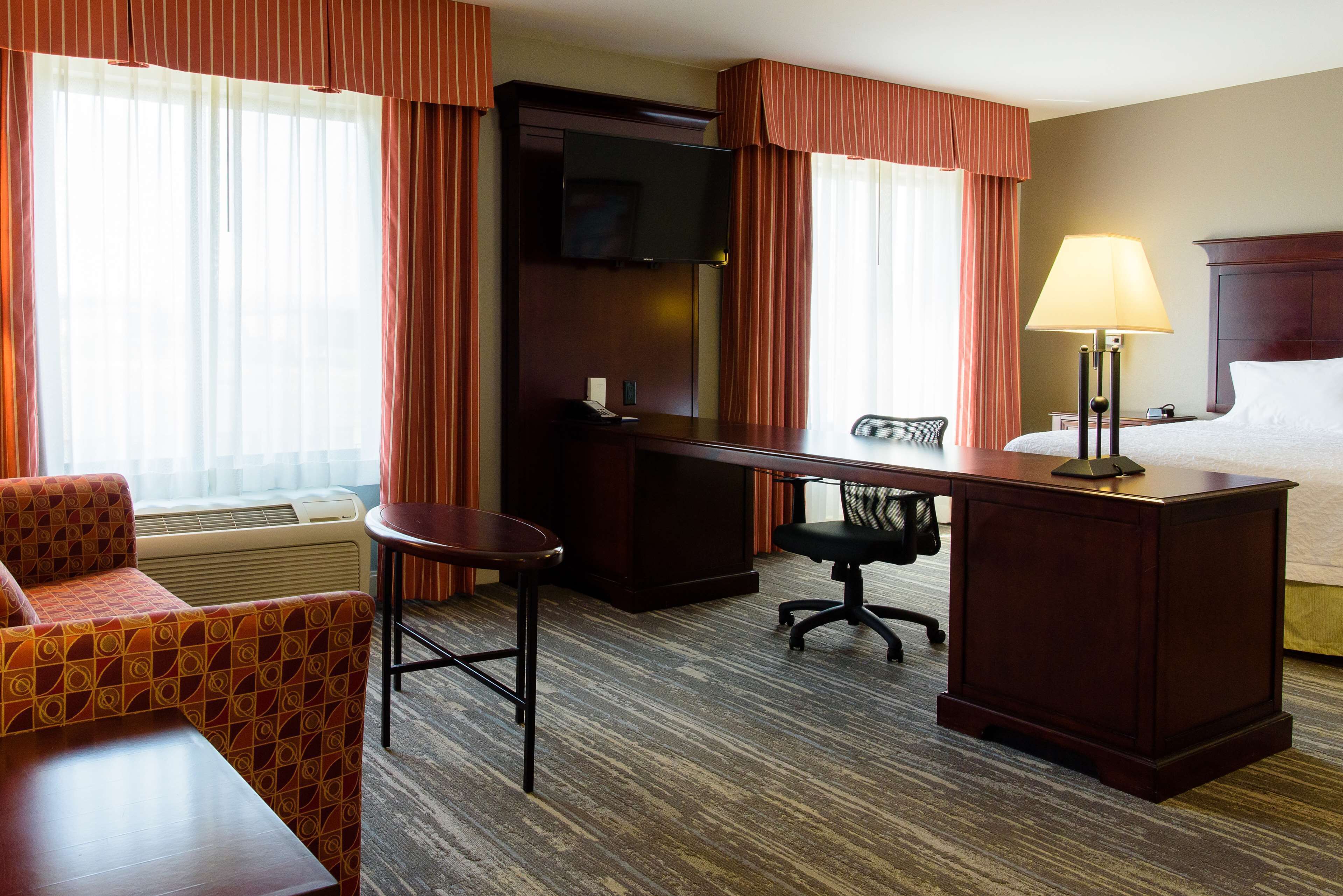 Une chambre d’hôtel avec un lit, un bureau, une chaise, une télévision et une lampe.