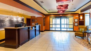 A hotel reception area with a wooden reception desk, a large window, and a chair.