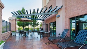 An outdoor patio area with a pergola, seating, and a brick wall.