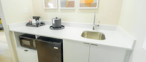 Una cocina compacta equipada con microondas, refrigerador, pileta y cafetera.
