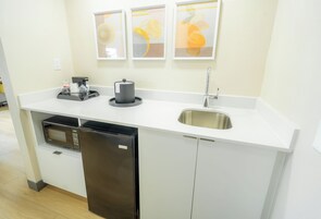 Una cocina compacta equipada con microondas, refrigerador, pileta y cafetera.
