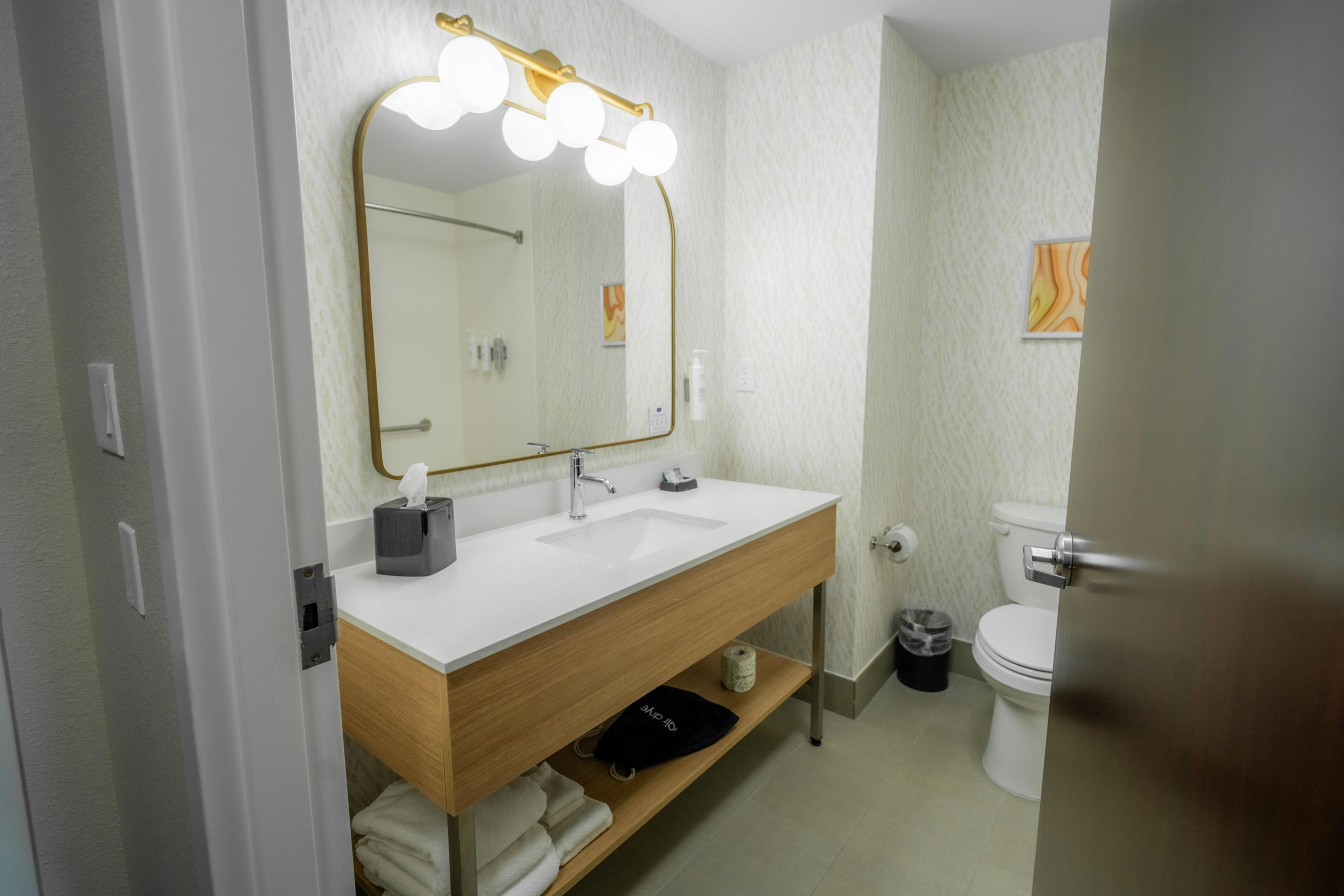 Un baño con tocador, espejo y retrete.