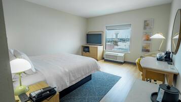 Une chambre d’hôtel équipée d’un lit, d’une table de chevet, d’une lampe, d’un bureau, d’une chaise et d’un téléviseur.
