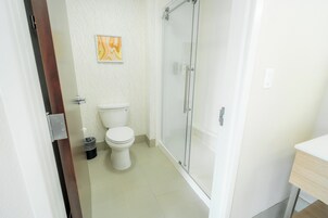 A bathroom with a toilet, a glass shower enclosure, and a sink.