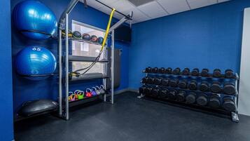 A gym with exercise equipment, including a pull-up bar, medicine balls, and a rack of dumbbells.