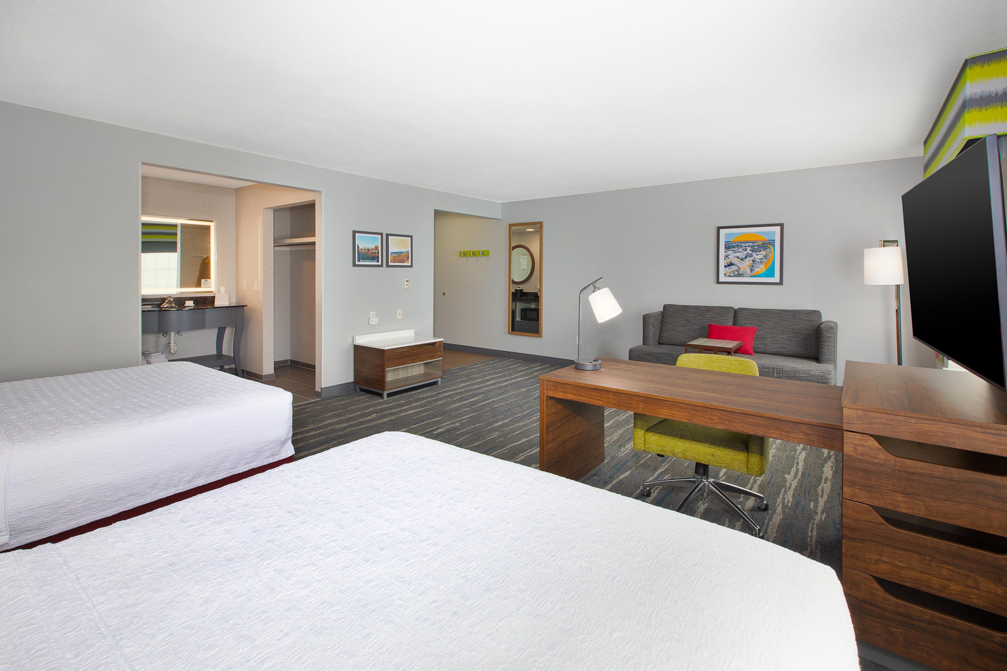 Une chambre d’hôtel avec deux lits, un bureau, un canapé, une télévision et une salle de bain.
