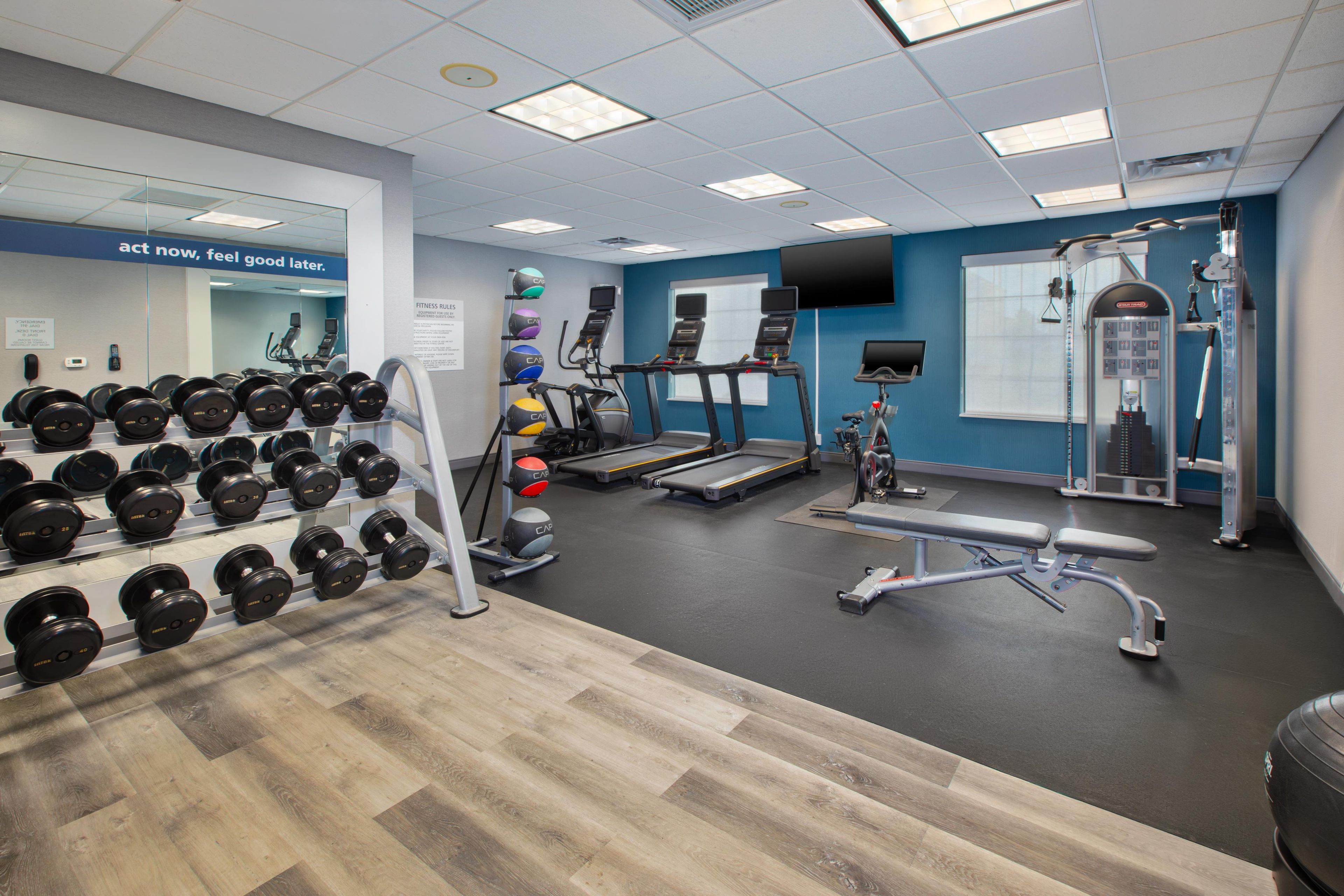 Une salle de sport équipée de tapis de course, d’appareils de musculation et d’une variété d’haltères.