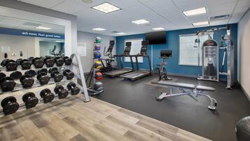 Une salle de sport équipée de tapis de course, d’appareils de musculation et d’une variété d’haltères.
