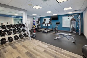 A gym with treadmills, weight machines, and a variety of dumbbells.