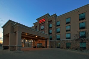 A Hampton Inn & Suites hotel with a covered entrance, stone facade, and multiple windows.