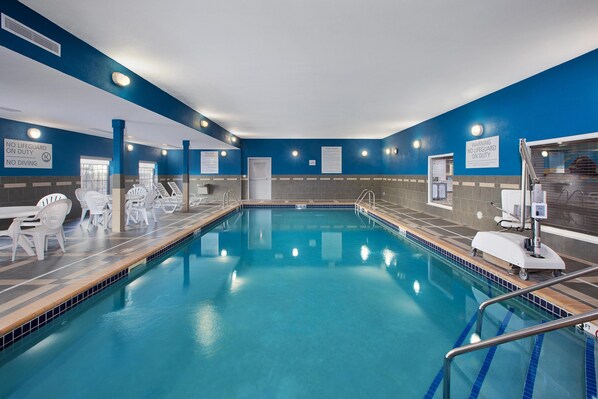 An indoor swimming pool with clear signage, lifeguard duty information, and a tiled floor.
