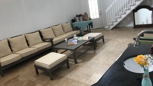 Un moderno hall de entrada con un sofá modular, una mesa baja, una pequeña mesa con un florero y una escalera.