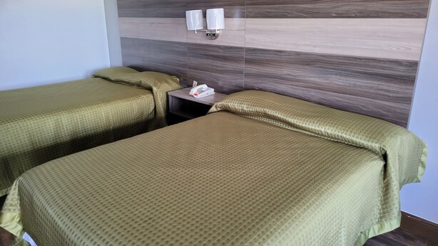 Ein Hotelzimmer mit zwei Einzelbetten, einem Nachttisch mit Telefon und einer Wandleuchte.
