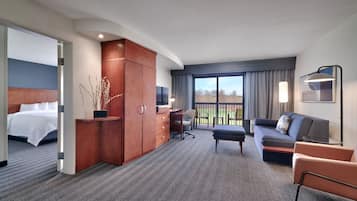 Une chambre d’hôtel avec un lit, un bureau, un canapé et un balcon offrant une vue.