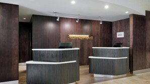 Un espace d’accueil doté de deux comptoirs de réception en bois foncé, d’un luminaire moderne suspendu au plafond et d’une enseigne indiquant le nom « Bonavoy ».