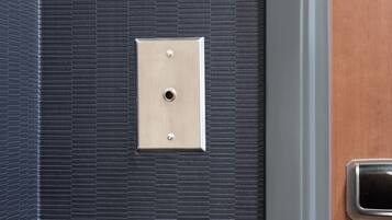 Un interruptor metálico en una pared texturizada, probablemente parte del sistema eléctrico de una habitación.
