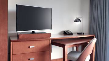 Una camera d'albergo con una scrivania in legno, una televisione, un telefono e una sedia.