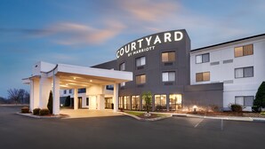 Un hôtel Courtyard by Marriott doté d’une entrée couverte, de nombreuses fenêtres et d’une façade bien éclairée.
