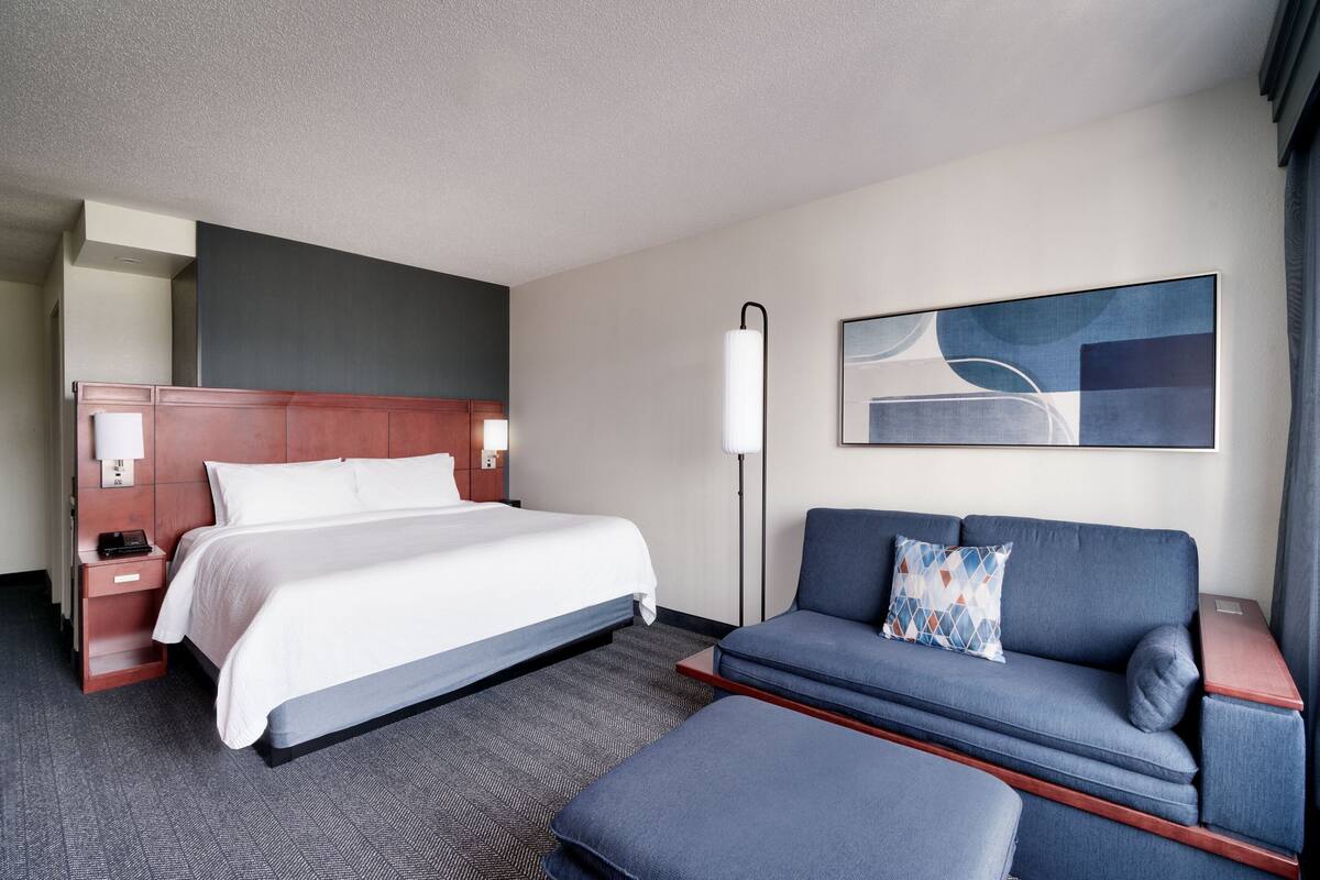 Ein Hotelzimmer mit einem großen Bett, einer Couch, einem Schreibtisch und einer Lampe.