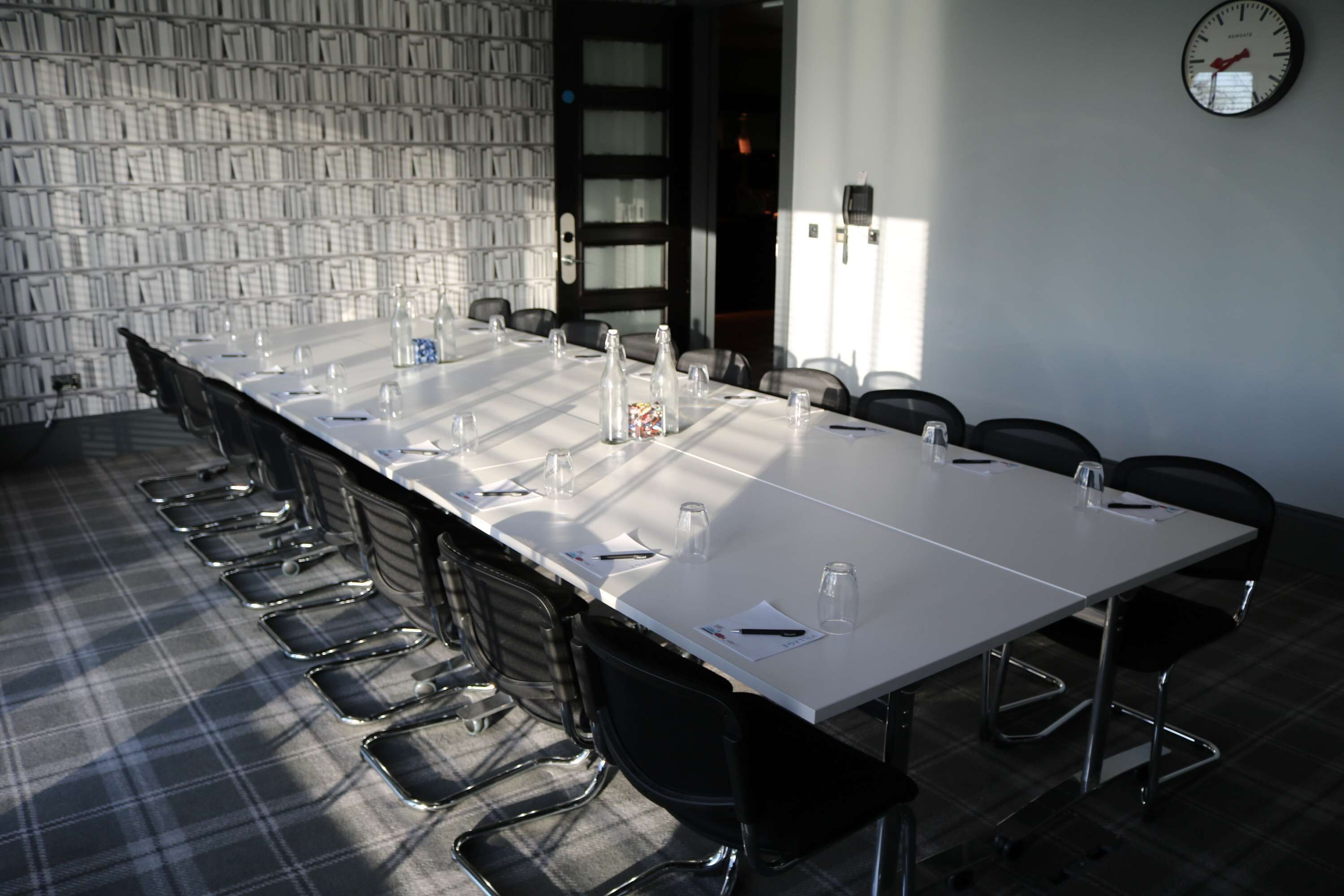 A conference room with a long table, chairs, and a clock on the wall.
