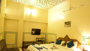 A hotel room with a bed, a TV, a desk, and a chair.