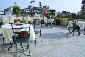 Terraço no telhado com área de estar ao ar livre, plantas em vasos e vista para edifícios próximos.