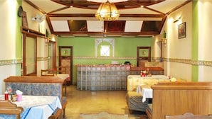 A hotel room with a large bed, a small table, a bench, and a chandelier.