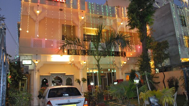 A hotel with a sign reading "HOTEL" and "HOTEL BANGKOK". There is a car parked in front, and the building is decorated with string lights.