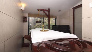 Experience a serene retreat with a traditional aesthetic, featuring a wooden bed and a large window overlooking lush greenery.