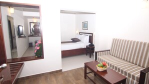 A hotel room with a bed, a sofa, a table with fruit, a mirror, and a staircase. - Abad Copper Castle (Devikolam)