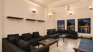 Una sala moderna con un sofá modular, una mesa de centro y vista al agua al atardecer.