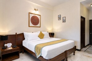 A hotel room with a bed, bedside tables, a lamp, and wall-mounted artwork. - Hotel Sarovar on Lake Pichola (Udaipur)