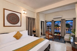 Une chambre d’hôtel avec un lit, un bureau, une chaise et une vue sur une étendue d’eau.