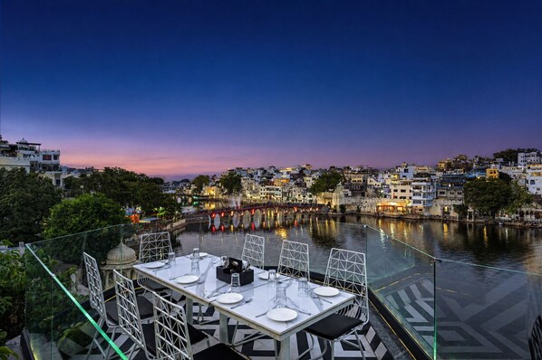 A table set for dining with a view of a river and cityscape at dusk.