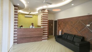 Un'area reception con scrivania, una ventola a soffitto e un divano nero.
