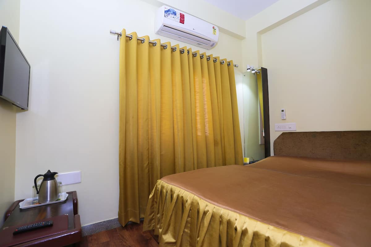 Una habitación de hotel con cama, televisión, cafetera y aire acondicionado.