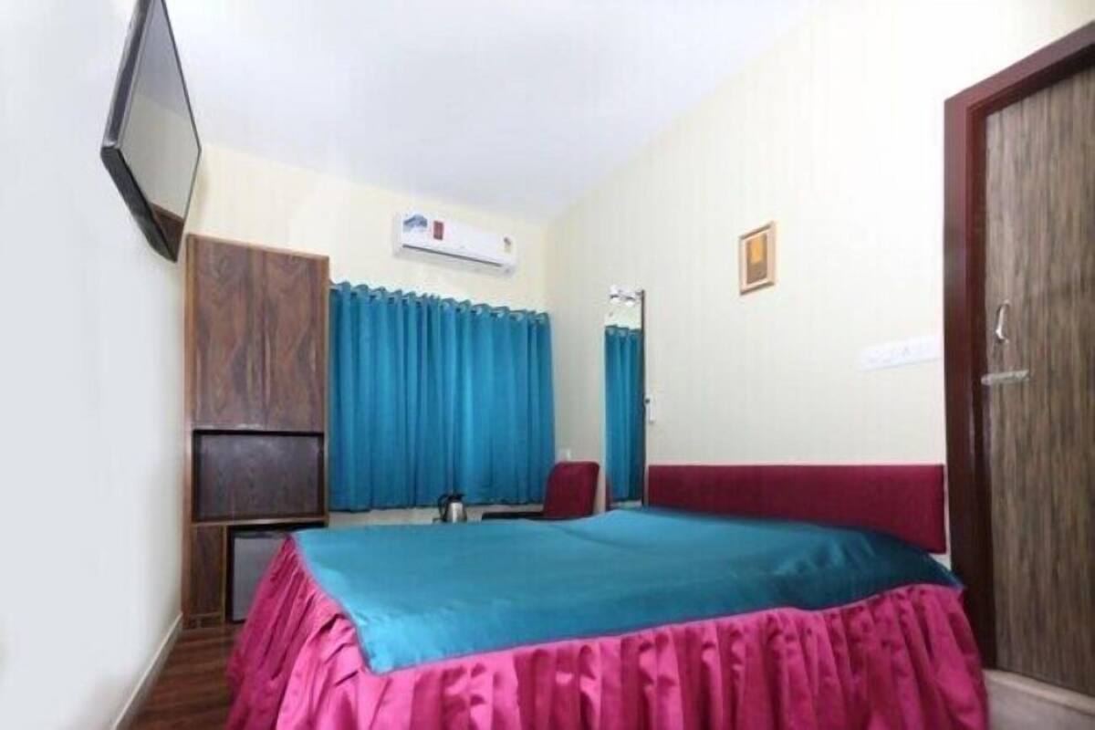 Un dormitorio con cama, televisor montado en la pared, armario y puerta.